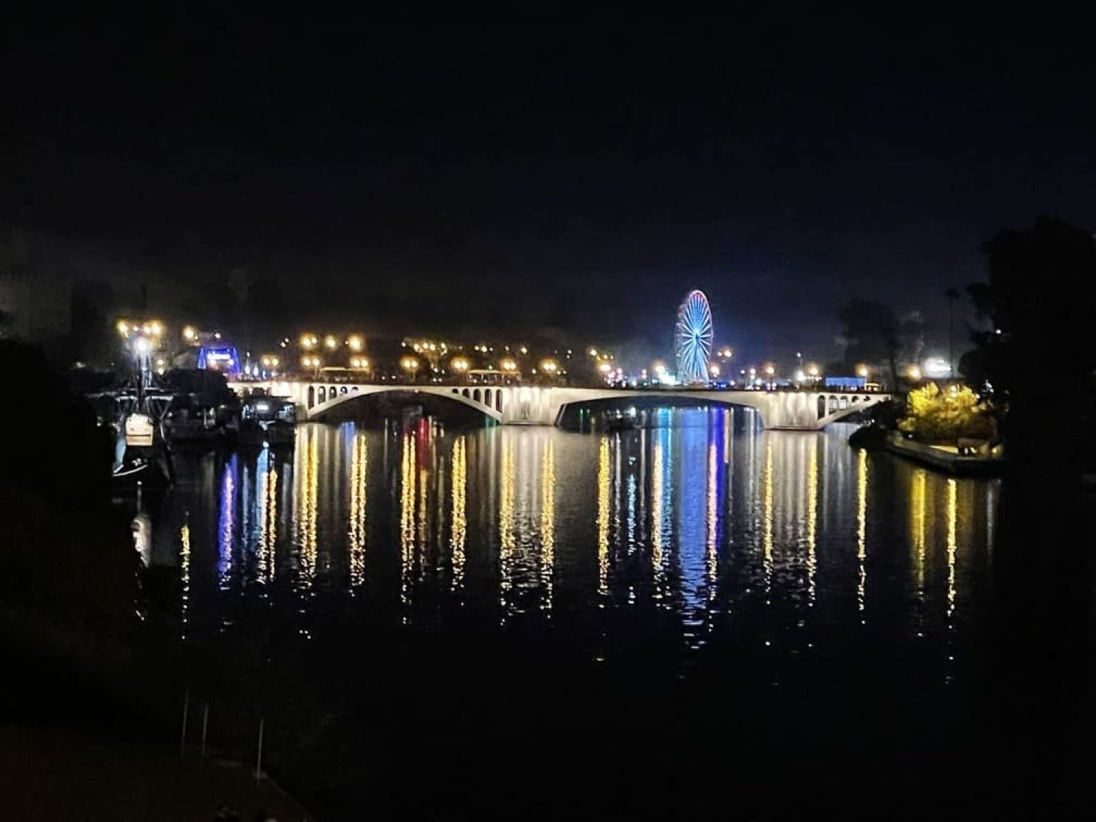 Río Guadalquivir y puentes de Sevilla iluminados durante la noche